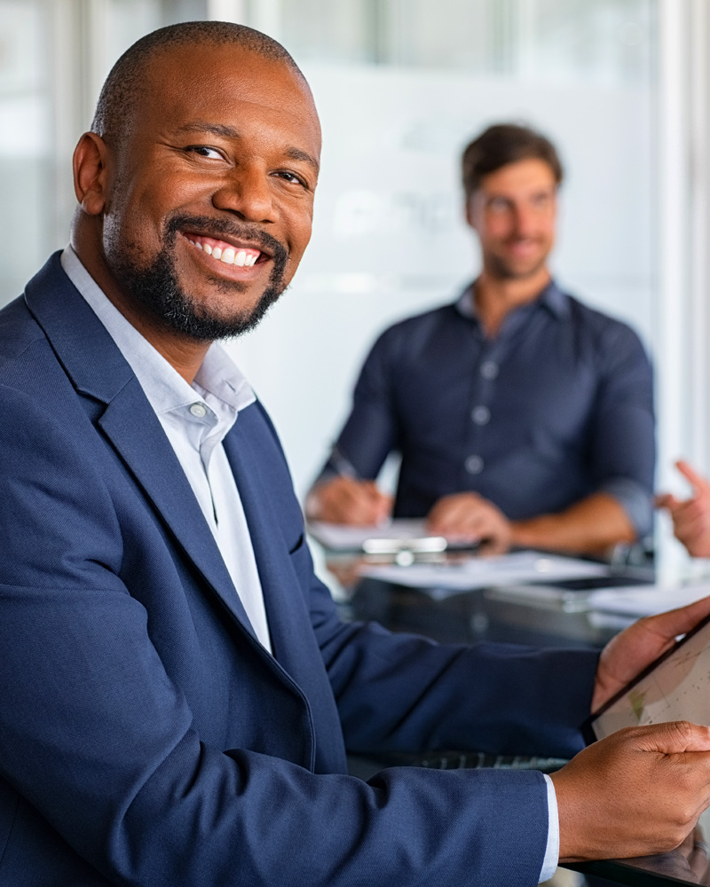 A confident black man in a suit leading a team meeting