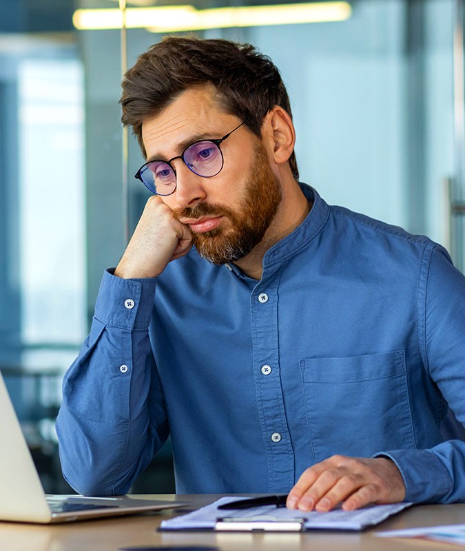 employee-disengagement-boredom-img Disengaged male employee looking bored at work