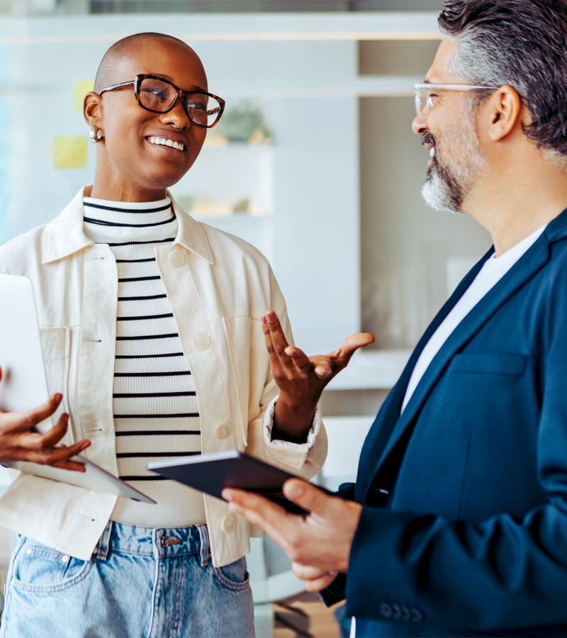 A black woman and a white bearded man engaged in conversation about a collaborative project they are excited about