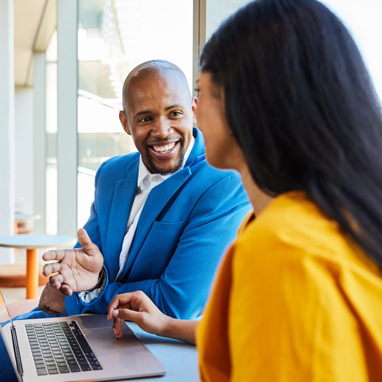 A black male executive personalizing a project assignment for a dark haired female employee