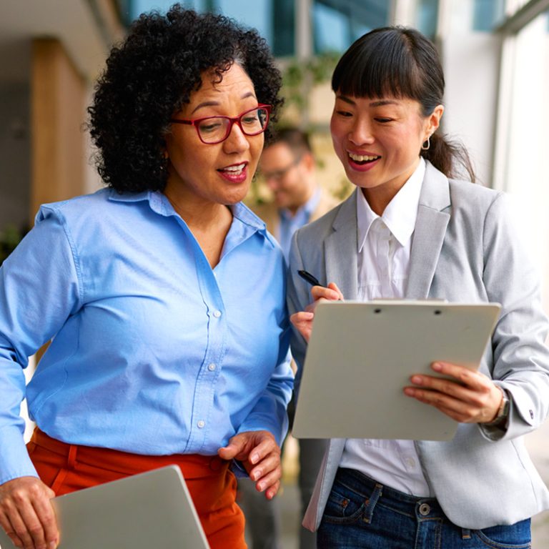 A Black woman and an Asian woman sharing their MCode results after a team workshop