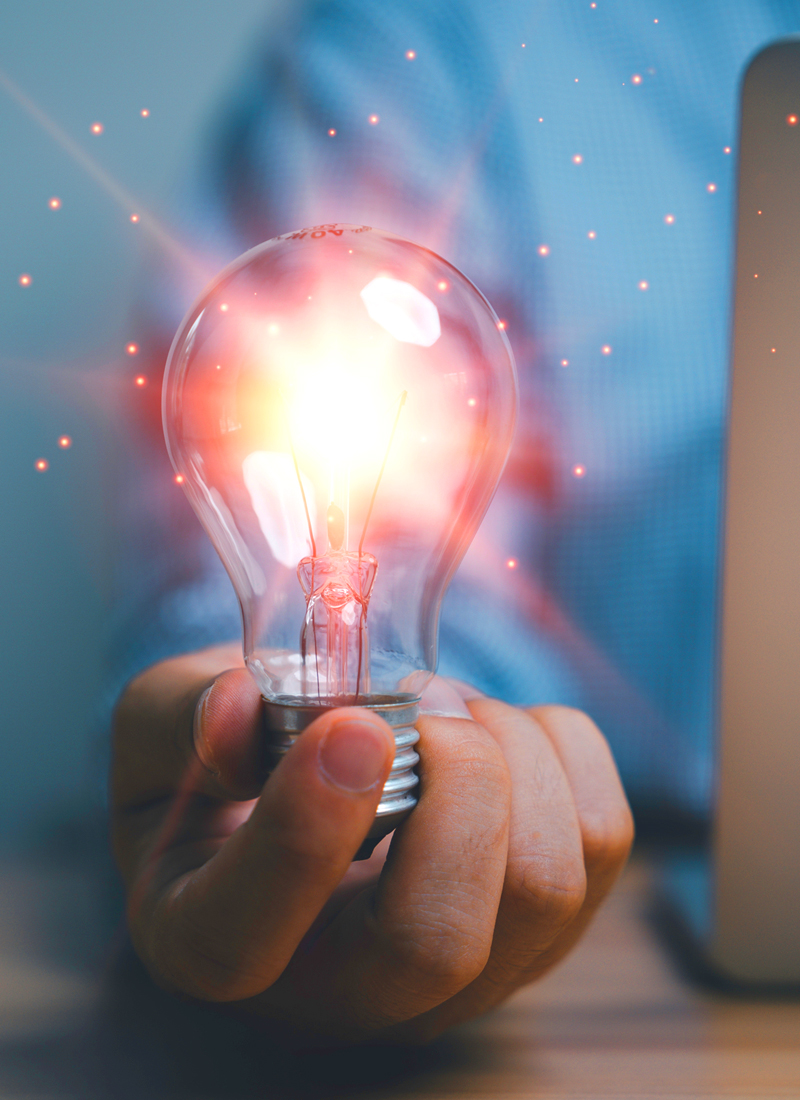 A man holding a lightbulb that is shining bright and exuding hues of pink and yellow to represent the aha of finally understanding how to leverage motivation to help employees grow