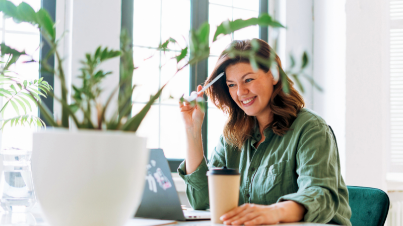 woman working in a light office with a plant on her desk