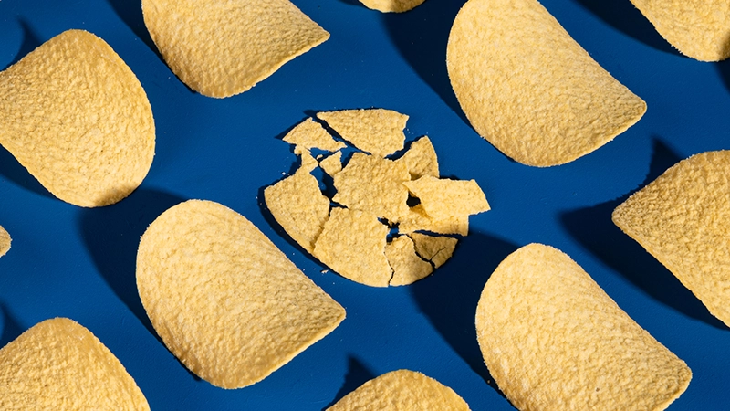 Pringles chips lined up in a grid pattern with one chip broken into little pieces to represent mistakes leaders make when managing high performers