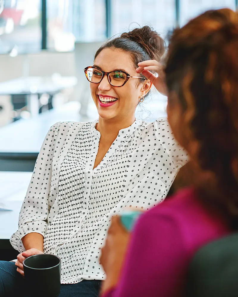 A woman drinking coffee and laughing with her colleagues